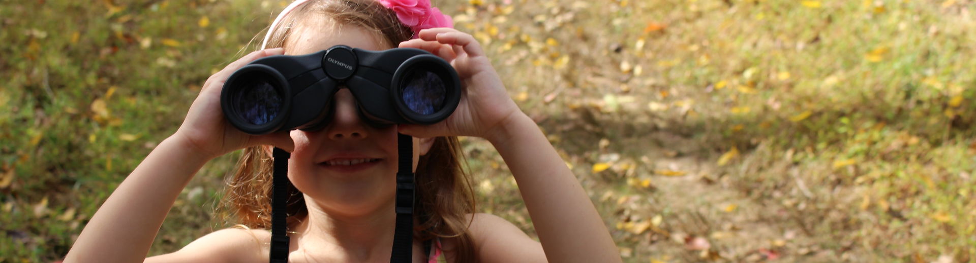 a girl with binoculars looking back at the camera