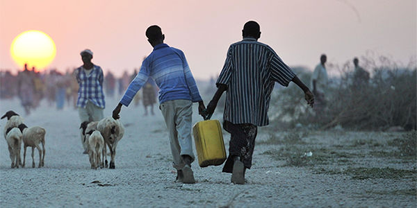 Two men carrying a pail of water